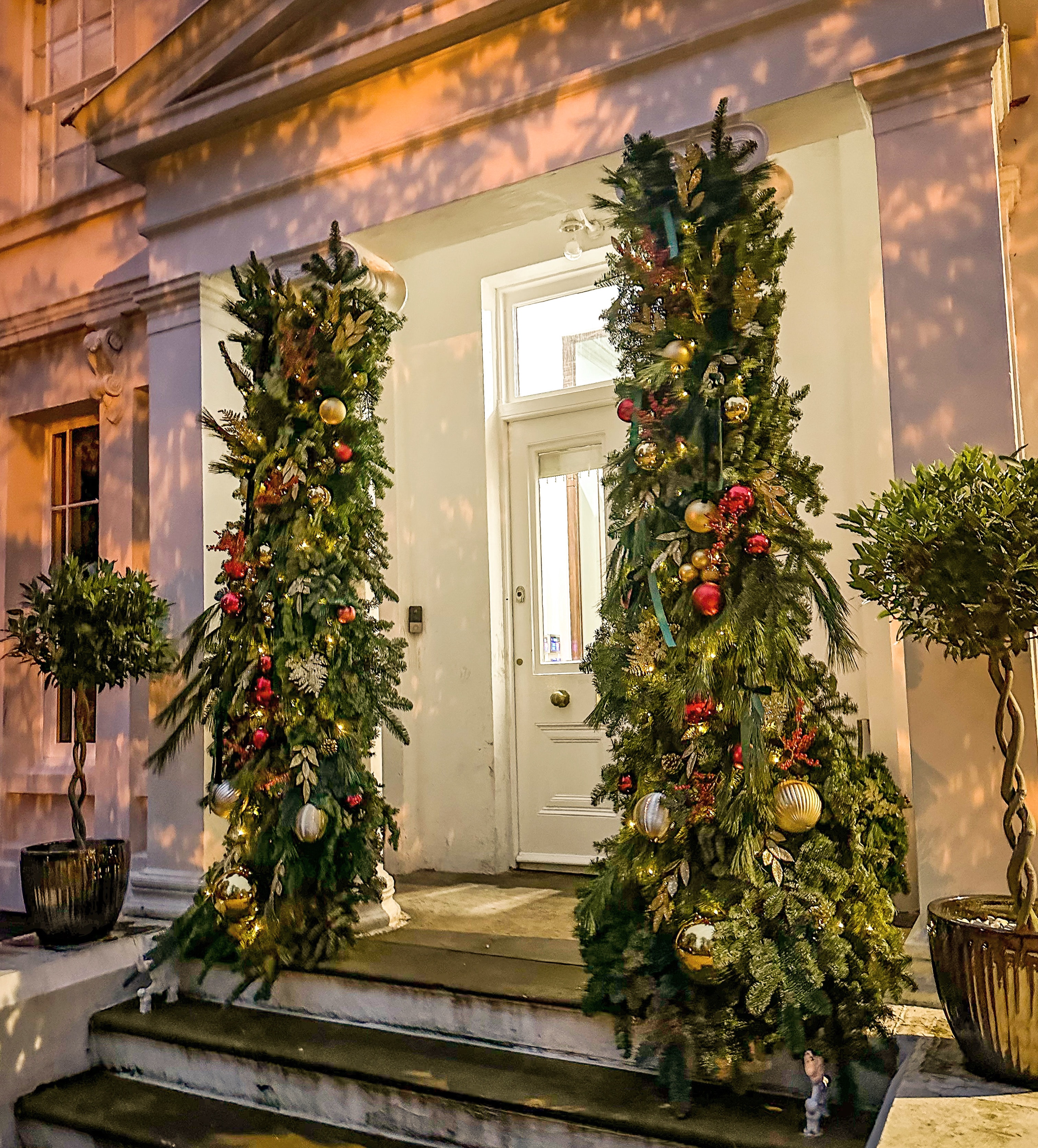 Grand exterior door garland columns with red and gold baubles at night