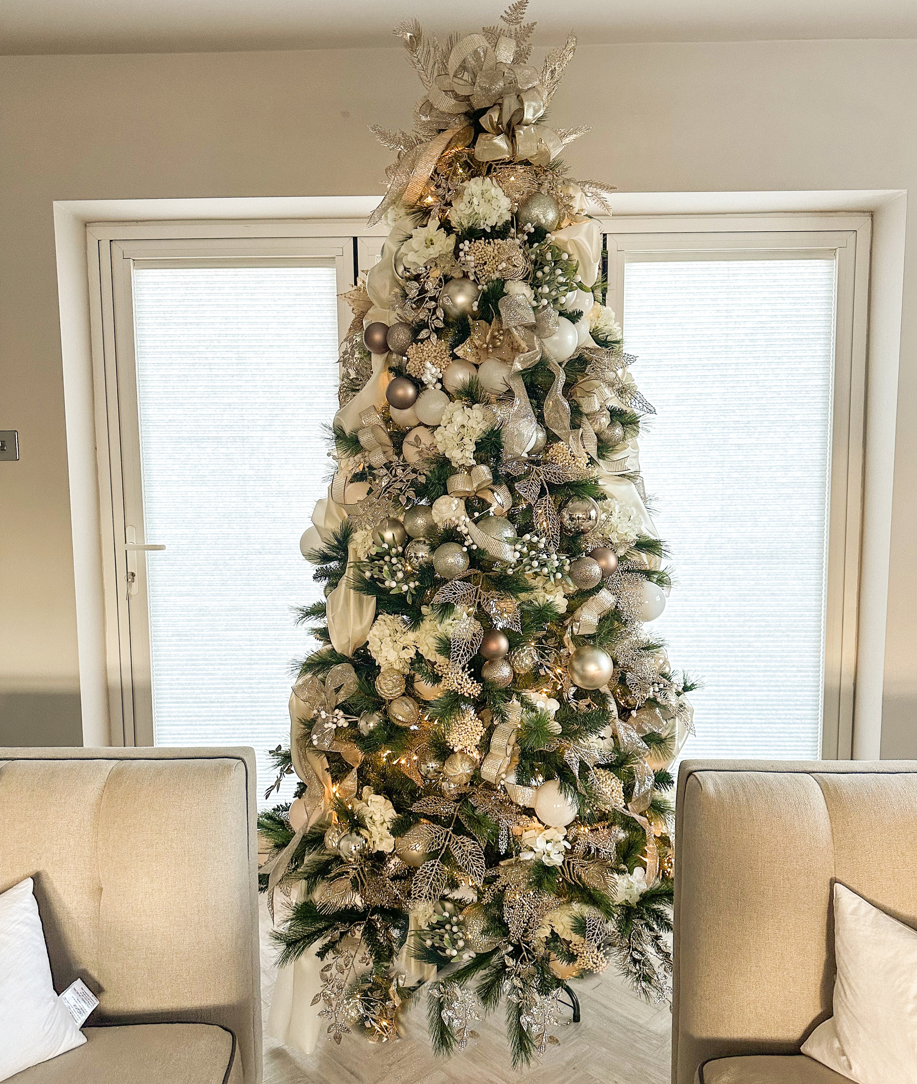 Stunning Christmas tree with cream and silver ornaments between armchairs
