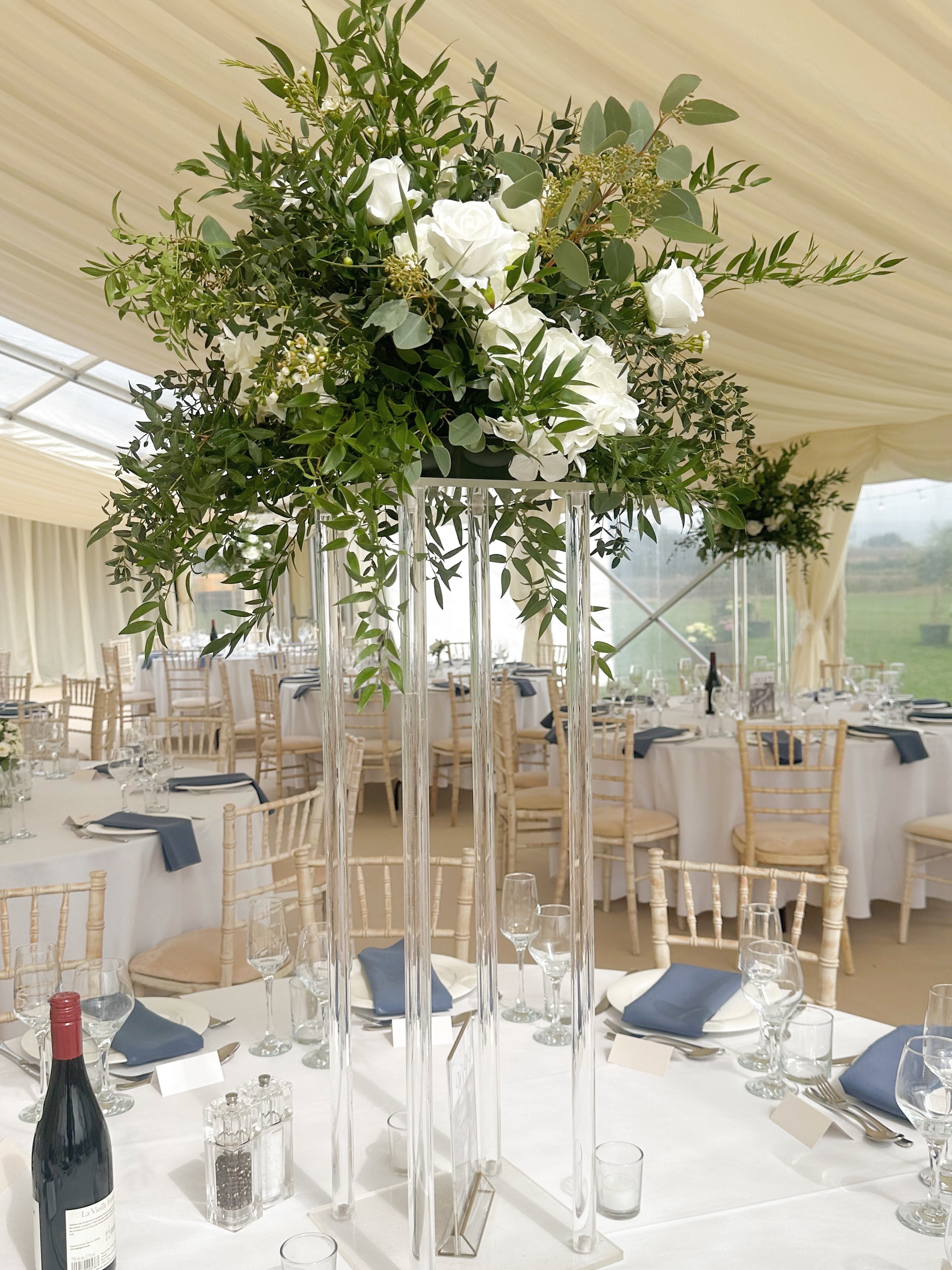 Marquee wedding reception with tall acrylic centrepiece and white roses