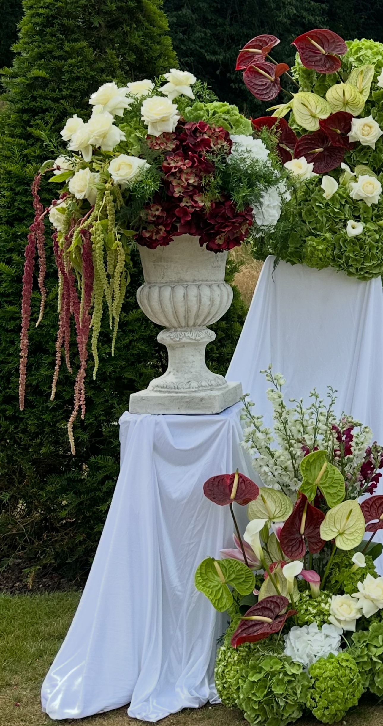 Stone urn with burgundy hydrangeas white roses and trailing amaranthus