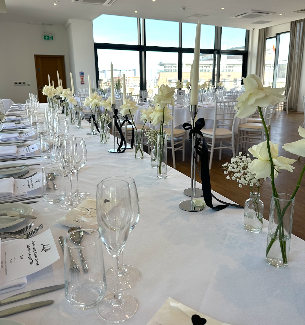 Modern venue wedding reception with white flowers and black ribbon candles
