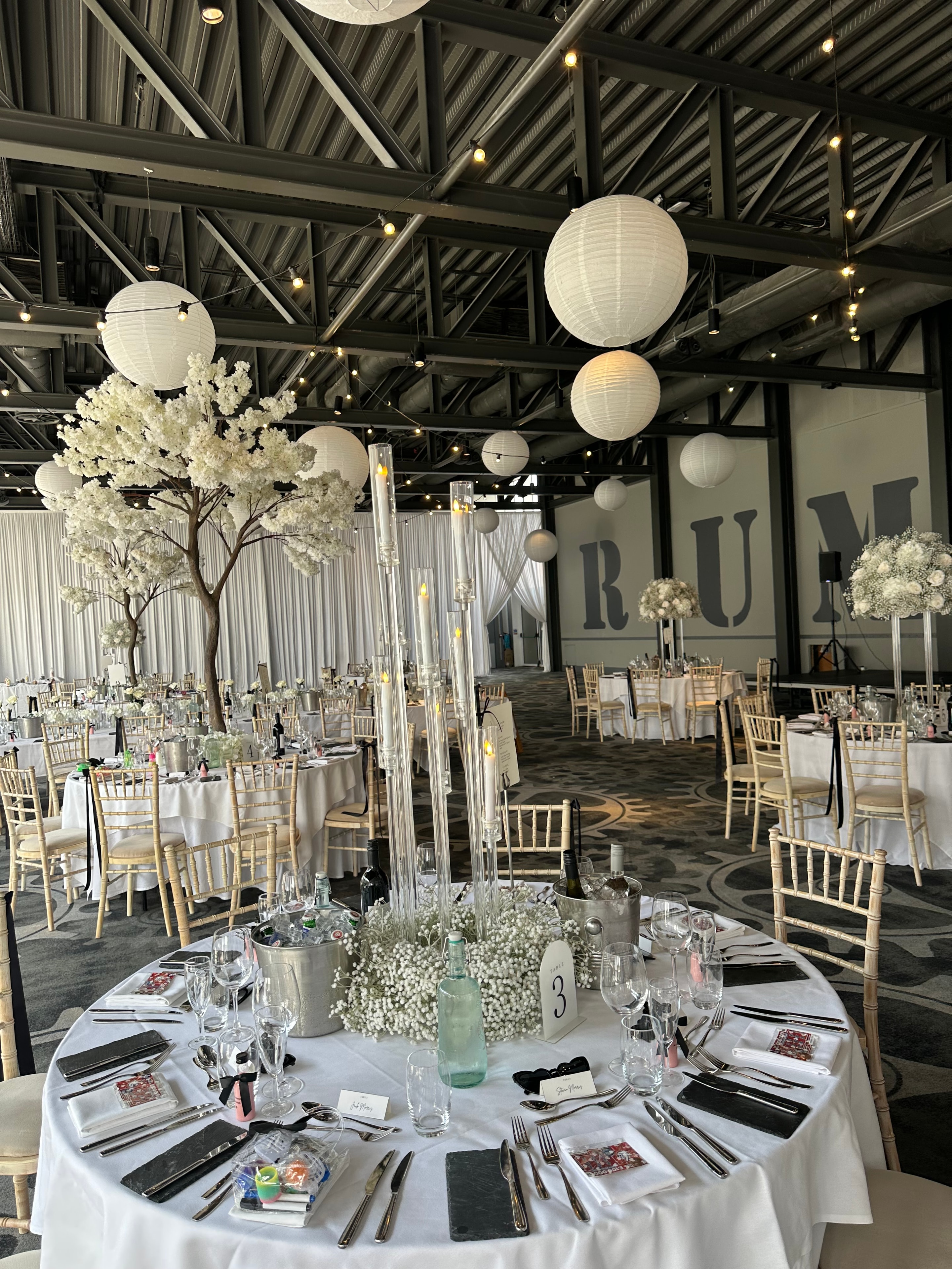 Industrial venue wedding with white paper lanterns and blossom trees