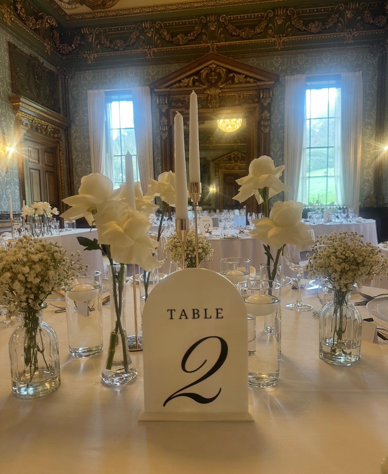 Ornate ballroom table setting with white flowers and table number