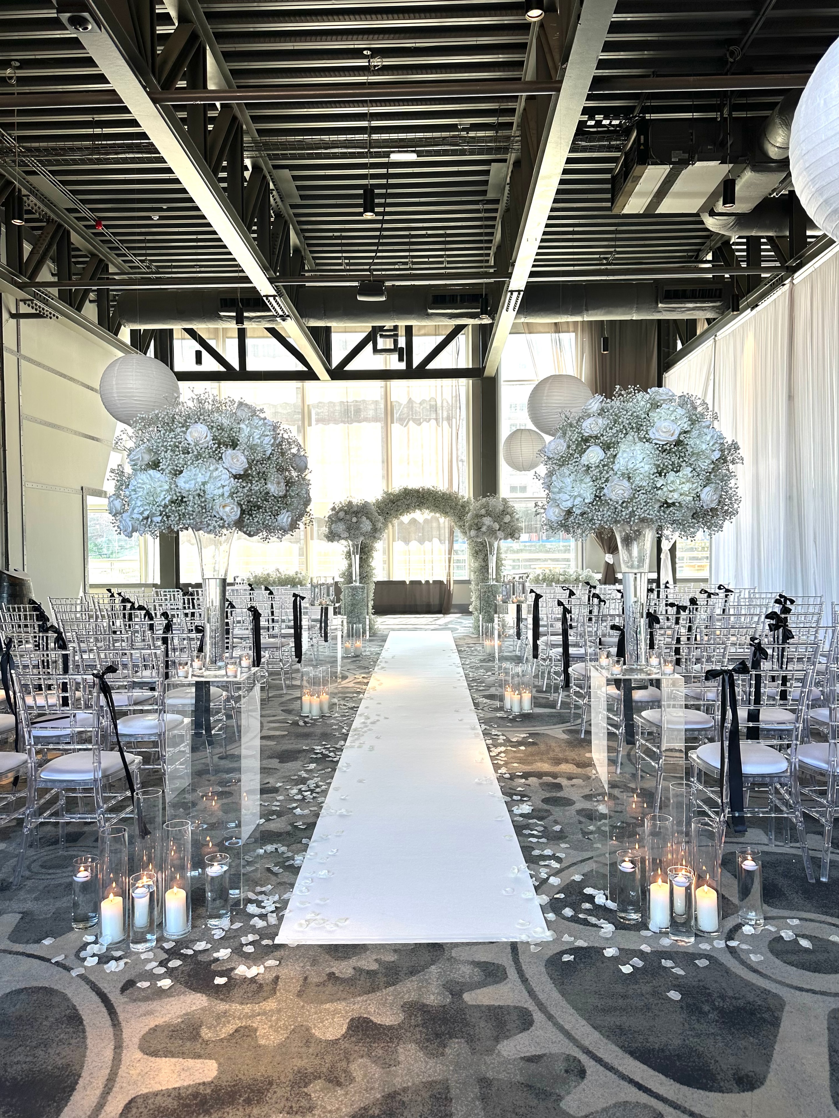 Industrial venue wedding ceremony with white gypsophila topiary trees and paper lanterns