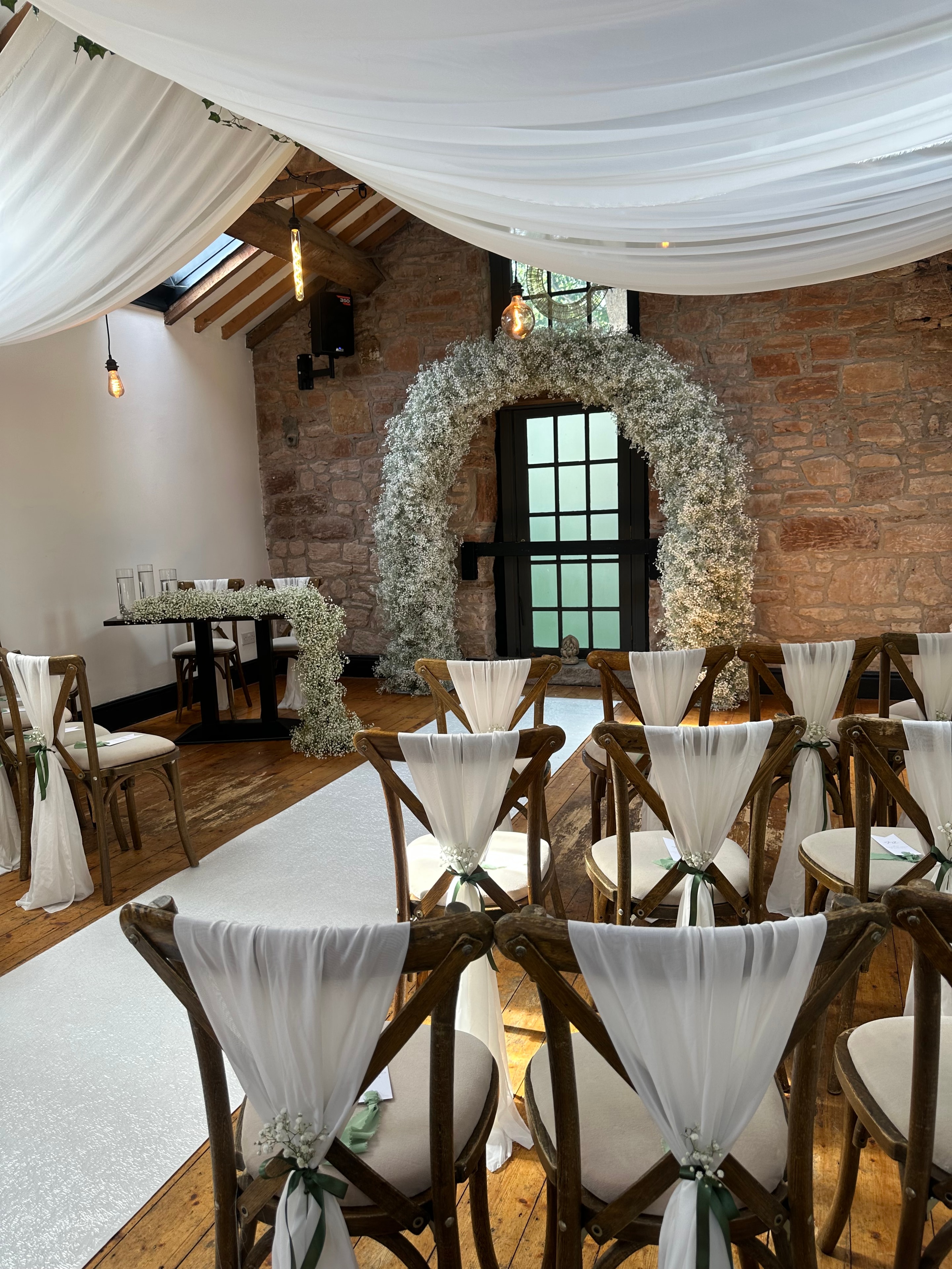 Rustic barn ceremony with gypsophila moon arch white draping and chiavari chairs
