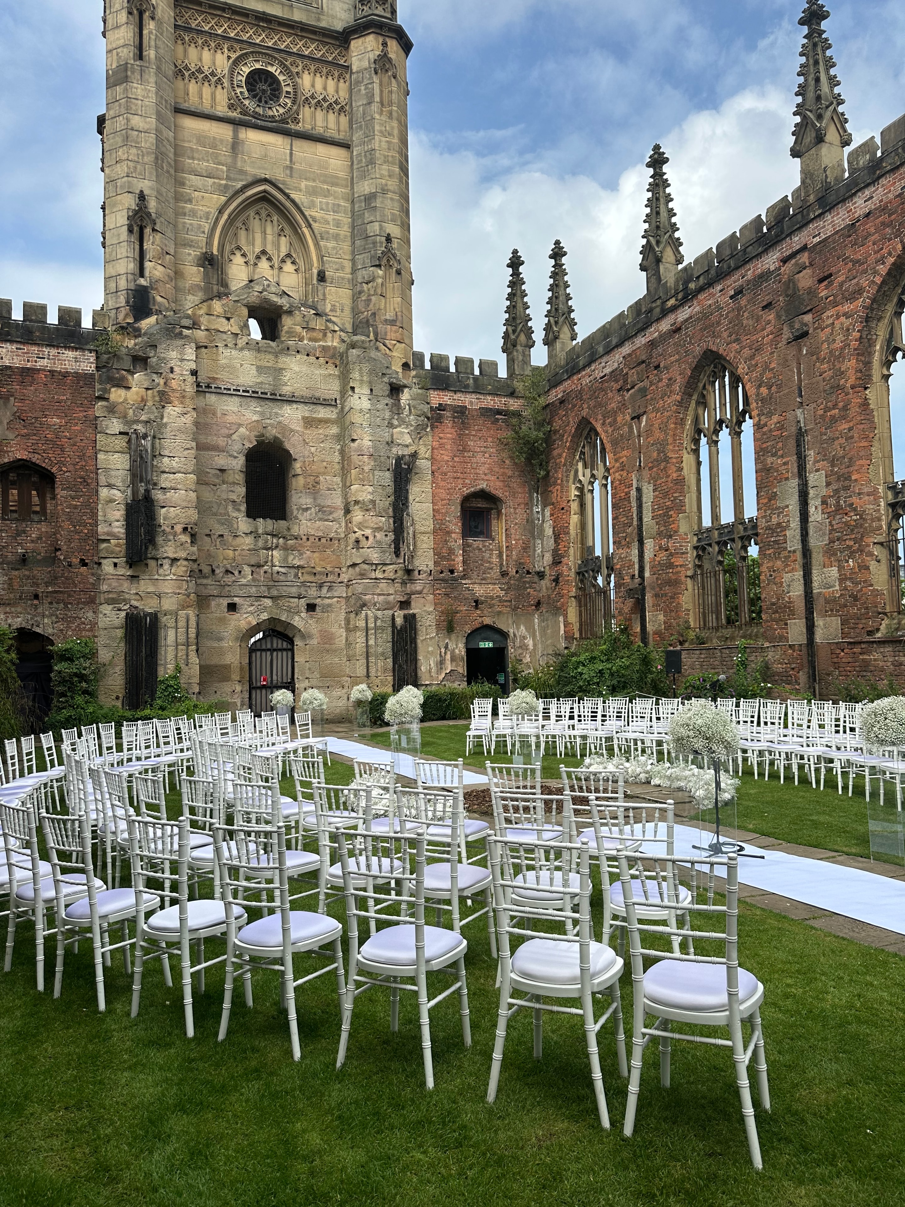 Outdoor ceremony at historic ruins with white chiavari chairs and gypsophila arch