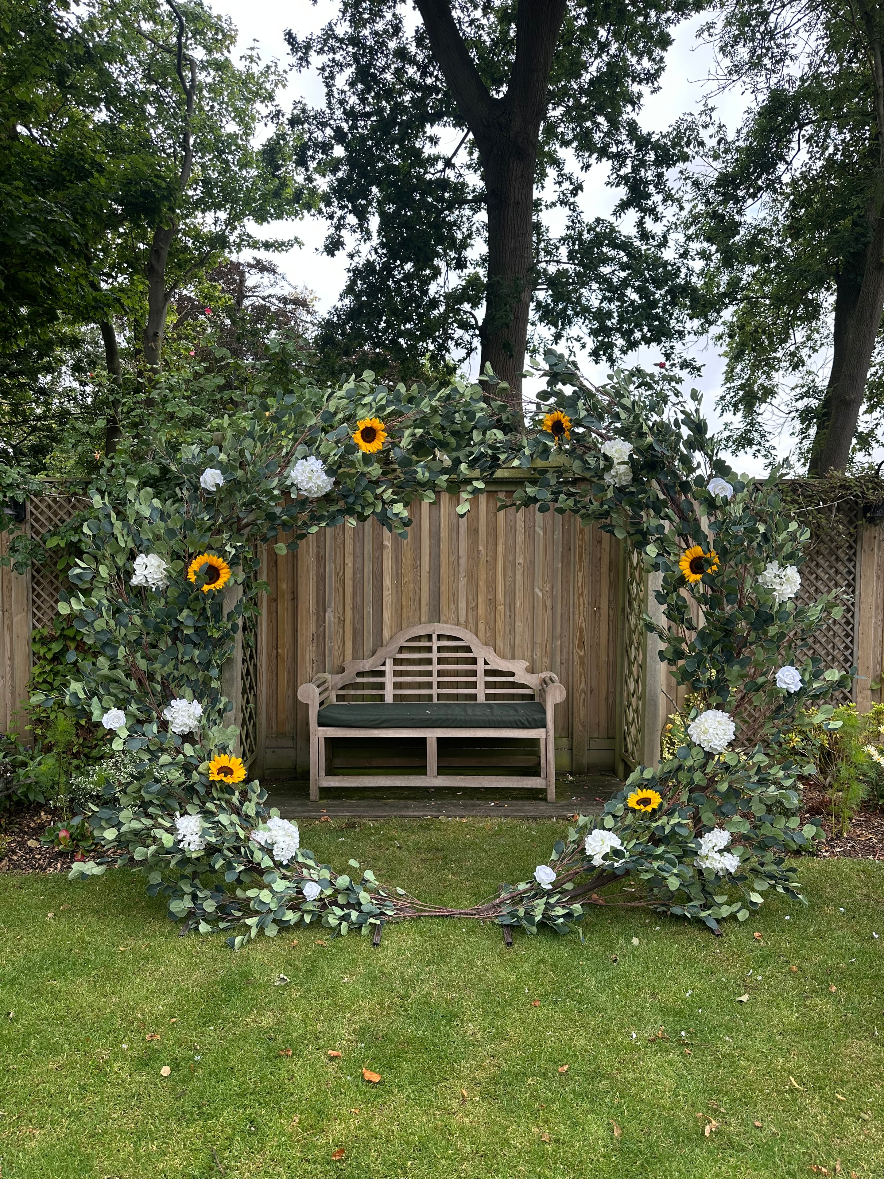 Garden arch with eucalyptus sunflowers and white hydrangeas at rustic outdoor venue